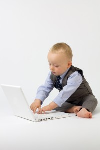 A cute baby boy is dressed in smart business clothes and is with his laptop ready for work. Studio shot Isolated on white.